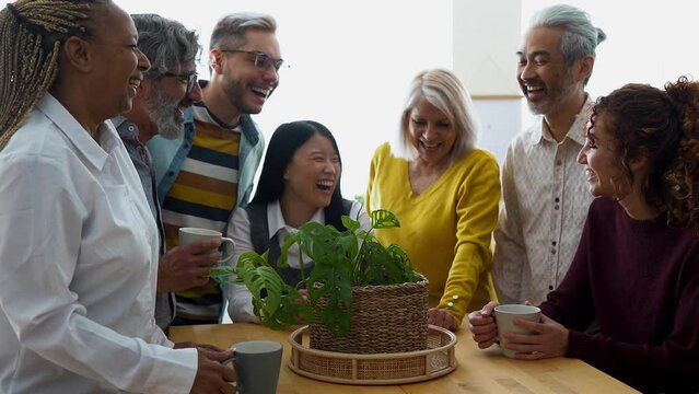 Multi generational people having fun inside kitchen at home while hugging each other - Multiethnic friends enjoy day together indoor

