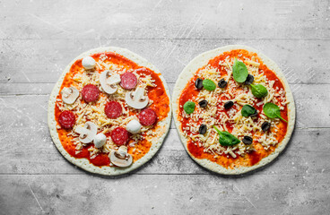 Two different raw pizzas.