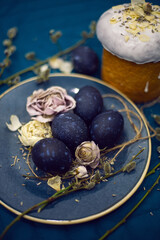 Kulich with sugar glaze .decoration design blue easter eggs lie on a plate with a willow on fabric background. Paska Easter Bread