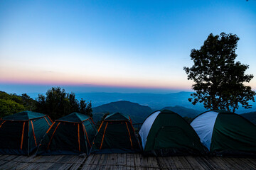 View of tents camping at the campsite in the woods with mountain range background. View of tents...