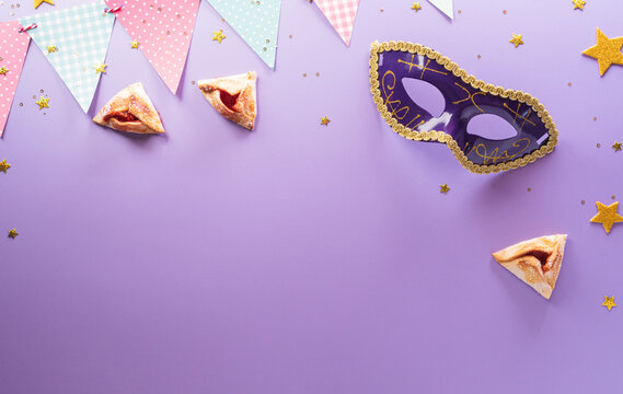 Happy Purim carnival decoration concept made from mask and sparkle star and hamantaschen cookies on pastel background. (Happy Purim in Hebrew, jewish holiday celebrate)