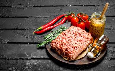 Raw minced meat with spices and jar of mustard .