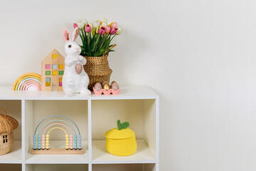 Home interior with easter decor.  White shelving with spring flowers, Easter Bunny, eggs and ...