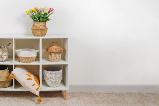 Home interior with spring decor. White shelving with various baskets and bouquet of tulips. Seagrass Belly basket , Cloth, and wicker  baskets for storage laundry and toys or can use as cachepot.