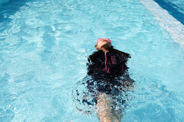 girl wearing black swimsuit Was swimming in the pool. in the concept of hobbies, summer, leisure activities, children swimming. soft and selective focus. 
