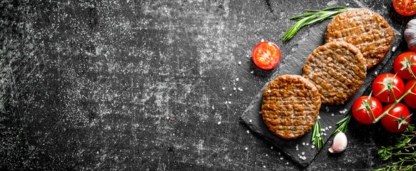 Obraz na płótnie Canvas Cutlets on a stone Board with tomatoes and garlic.