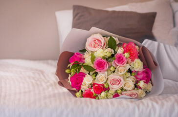 A bouquet of pink roses on a white bed, brought in the morning for your beloved as a gift.