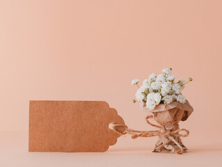 miniature bouquet of gypsophila is wrapped in kraft paper with an empty tag. Greeting card