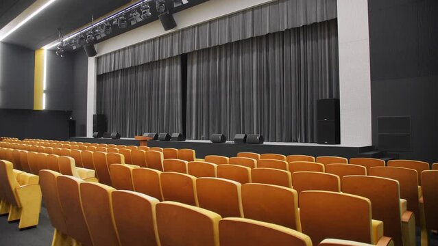 Chair rows and stage with black curtain in empty hall of theatre. Enclosure with furniture and space for performance