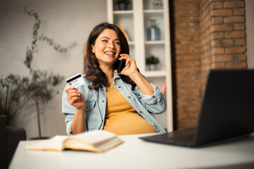 Pregnant woman shopping online at home. Happy woman with laptop and credit card.