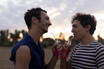 Fototapeta premium Happy young couple enjoy at the beach. Men drinking juice. LGBT community