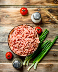 Raw minced beef in a bowl with tomatoes and green onions.