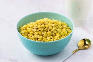 Breakfast cereal close-up. Bowl of corn flakes on a white marble table