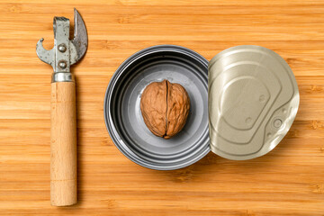 Can opener and opened tin can with a single walnut inside