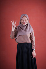 Fototapeta na wymiar Beautiful Asian woman in brown shirt and hijab showing and pointing up with finger number three while smiling confident and happy on brown background