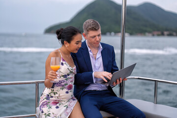 Business man and girl friend on holiday sailing on the yacht check laptop and get good news