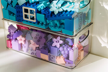 Transparent plastic containers with various colorful rainbow colored constructor pieces. Toy bricks sorting by colors. Storage Ideas in nursery. Space organizing at childrens room. Toys sorting system