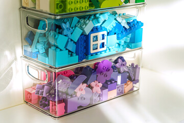 Naklejka premium Lego duplo. LEGO blocks sorting by colors in transparent plastic containers. Storage Ideas in nursery. Space organizing at children's room.