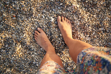 Female feet standing on pebbles at the beach, top view