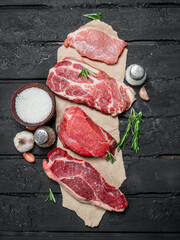 Raw meat. Pork and beef steaks with spices and herbs.