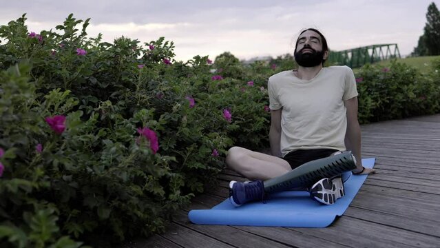 Fit man with disability wearing bionic hi-tech leg prosthesis doing meditation routine outdoor