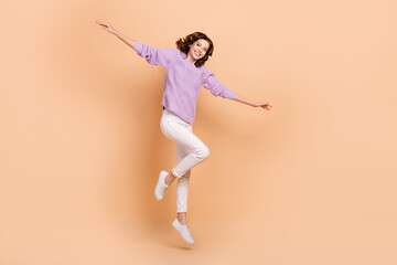 Fototapeta na wymiar Full length photo of cheerful lady wear purple stylish clothes rejoice dream fly abroad empty space isolated on beige color background