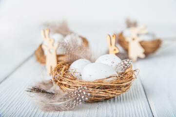 Obraz na płótnie Canvas Happy Easter greeting card. Miniature rabbits and nests with eggs and feathers..