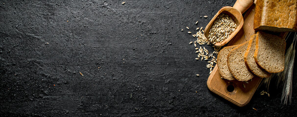 Pieces of bread on a cutting Board with spikelets and grain.