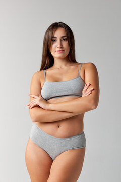 Well-being. Portrait of young beautiful girl posing in underwear over grey studio background. Concept of body and skin care, fitness