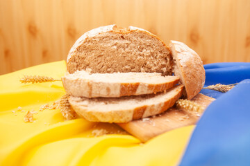 Fresh loaf of bread on the yellow and blue colors Ukrainian flag, deficit of wheat in Ukraine concept	