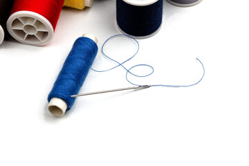 group of sewing spools and two needles isolated on white background with real shadows