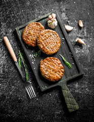 Cutlets on a cutting Board with garlic and a fork.