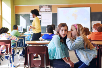 School, friends and whispering in classroom for secret, gossip or chatting during teaching lesson. Sneaky female learners sharing quiet information secretly in ear at class while teacher is busy