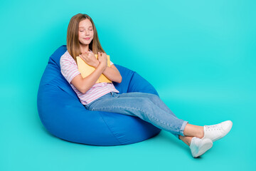 Full length photo of pretty tired lady wear t-shirt bean bag cuddling book empty space isolated turquoise color background