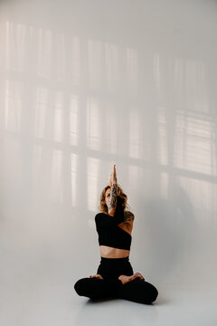 Woman with tattoos practicing Yoga with white background