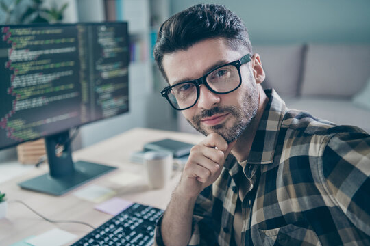 Photo of positive clever freelancer wear eyeglasses hand arm chin fulfilling task modern gadget indoors workplace workstation loft