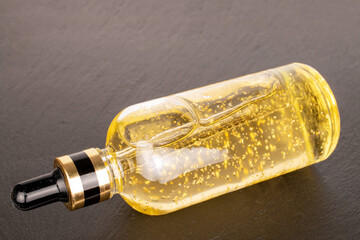 Fototapeta premium Face serum in glass bottle on slate stone, macro.