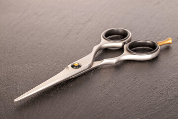 Obraz premium Metal scissors on slate stone, macro.