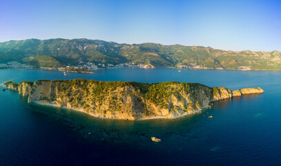 Panorama of island of St. Nicholas with vegetation in the Adriatic Sea against the backdrop of coastal towns, the Montenegrin mountains and clear sky