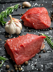Raw meat. Sliced pieces of beef with spices and herbs on a wooden Board.