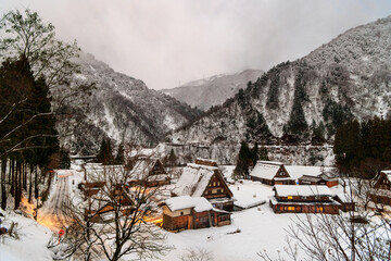 Lights on in snowy UNESCO World Heritage village in mountain landscape at dawn - 562139973