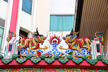 The Double Chinese dragons on the temple roof with blue sky background at Chinese Temple, Thailand