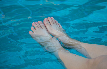 Woman's feet cooling in clear blue water