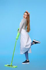 woman in rubber gloves and cleaner apron washing floor with mop