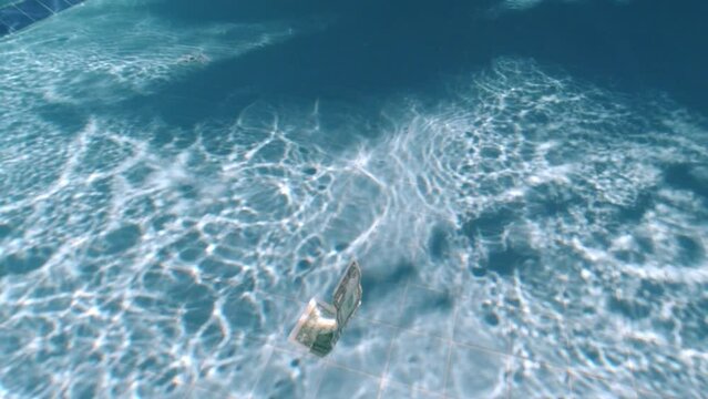 Banknote floats in the water. One dollar in the pool. Underwater photography. The banknote sinks to the bottom