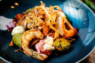Warm salad with Argentinian king prawns. Almond potato, mini romaine lettuce, carrot, cherry tomato, pesto, black root chips, caramelized walnut, beet balsamic. Food served in modern restaurant