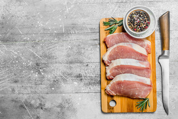Raw pork steaks with knife and spices.