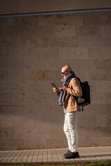 Side view of businessman walking and text messaging on his phone