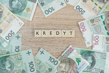 Word kredyt in Polish language, means loan or mortgage. Buying a house or apartment in Poland. Flat lay composition with złoty money, PLN zloty banknotes.	