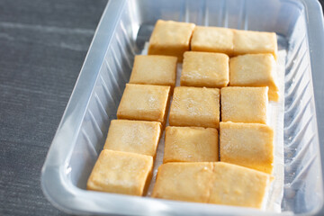 A view of a plastic container of fish tofu squares.